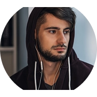 A man in a hoodie and headphones, focused and listening intently, with a neutral background.